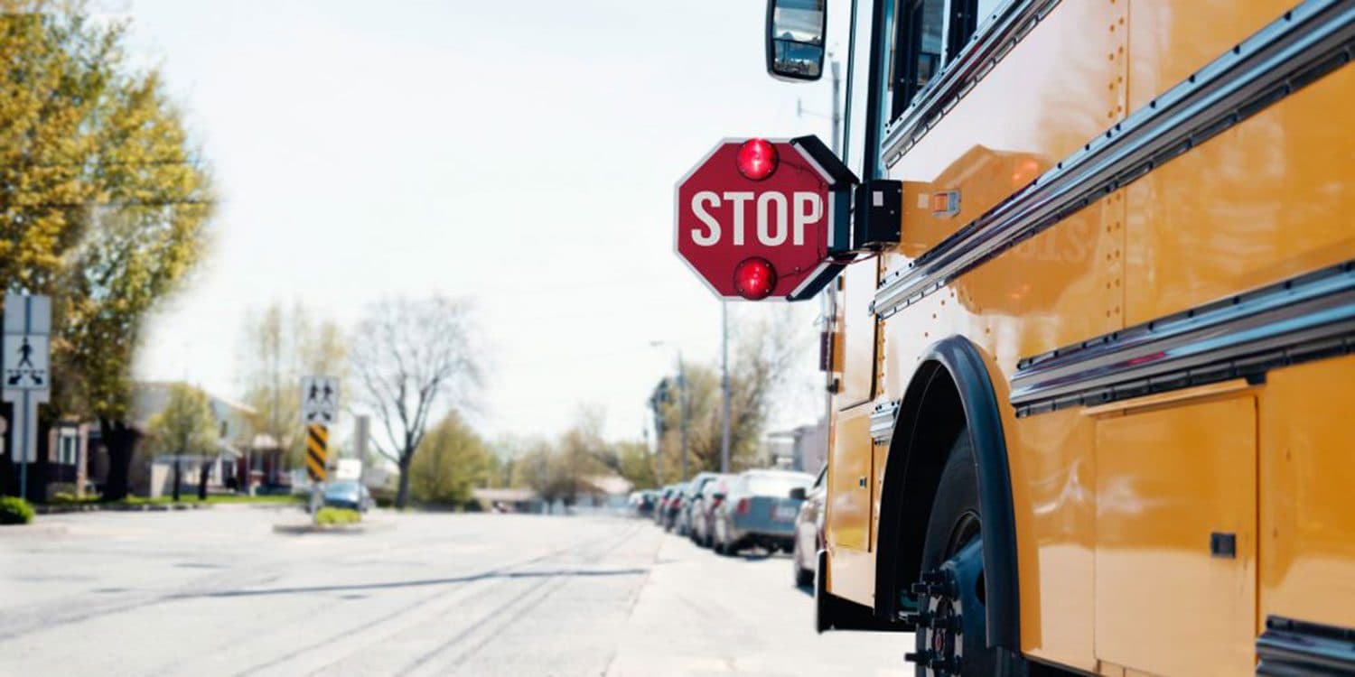 Yellow school bus stopped on a neighborhood street with its stop sign extended.