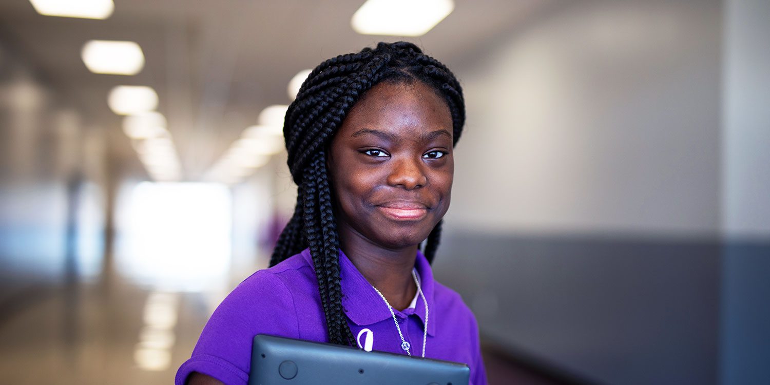 Smiling middle school student standing in hallway.