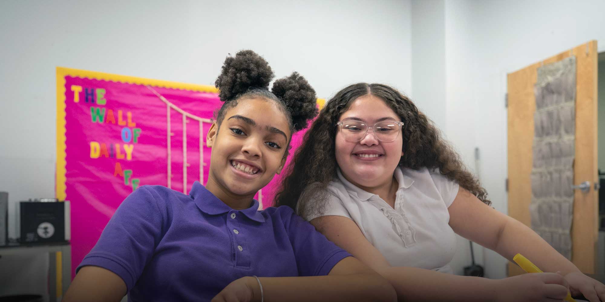 Two smiling students sitting in class
